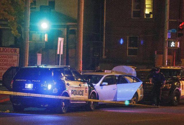 Police investigate the scene where a car crashed into a roadblock in Edmonton Alta, on Saturday, September 30, 2017. Police say a vehicle rammed a traffic control barricade and sent an officer flying into the air 15 feet. (Photo by Jason Franson/The Canadian Press via AP Photo)