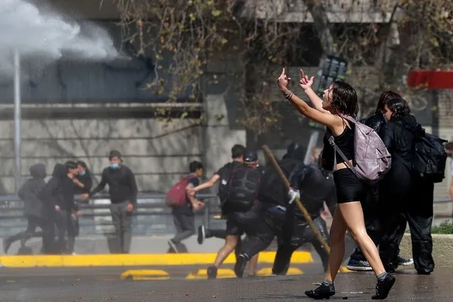 A student gestures at riot police during a protest outside La Moneda presidential palace in Santiago, on September 6, 2022. (Photo by Javier Torres/AFP Photo)