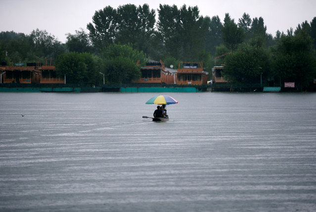 People use an umbrella to take cover from rains as they travel in a small boat on the waters of Dal Lake in Srinagar July 27, 2016. (Photo by Danish Ismail/Reuters)