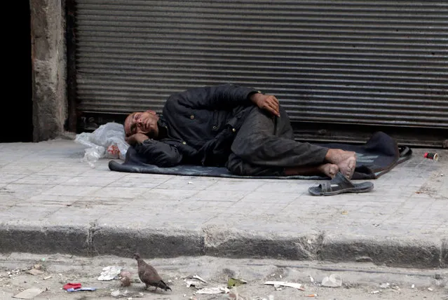 A man rests on the ground in the rebel held al-Shaar neighbourhood of Aleppo, Syria July 14, 2016. (Photo by Abdalrhman Ismail/Reuters)