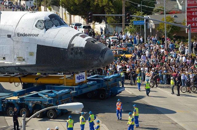 The Space Shuttle Endeavour is moved slowly along a city street October 12, 2012, in Los Angeles, California. The shuttle is on its last mission – a 12-mile creep through city streets, past an eclectic mix of strip malls, mom-and-pop shops, tidy lawns and faded apartment buildings. Its final destination is the California Science Center in South Los Angeles where it will be put on display.  (Photo by Mark J. Terrill-Pool)