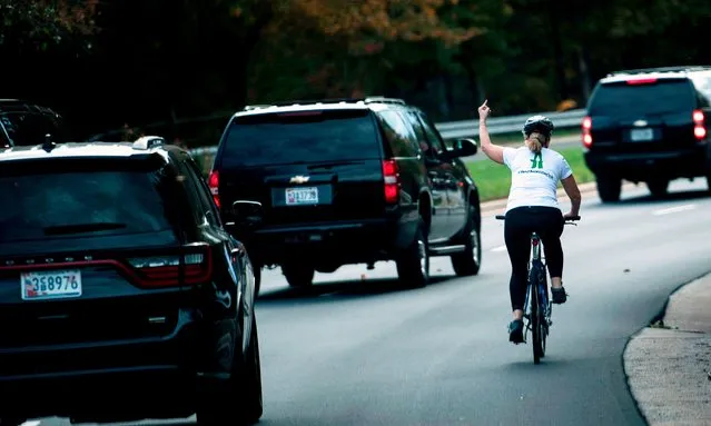 A woman on a bike gestures with her middle finger as a motorcade with US President Donald Trump departs Trump National Golf Course October 28, 2017 in Sterling, Virginia. (Photo by Brendan Smialowski/AFP Photo)