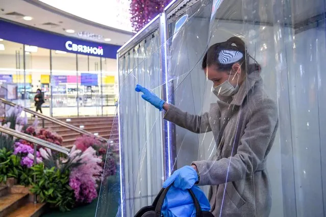 A woman wearing a protective face mask and gloves walks through a disinfection cabin at entrance of the Evropeyskiy shopping mall in Moscow on June 1, 2020. Moscow residents ventured out to exercise, stroll and shop on Monday as the city eased a strict nine-week lockdown, but millions remained largely confined to their homes as Russia recorded thousands more coronavirus cases. (Photo by Kirill Kudryavtsev/AFP Photo)