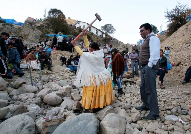 An Aymara woman tries to break a rock with a sledge hammer as part of the celebration of the Virgin of Urkupina on the outskirts of La Paz August 15, 2016. (Photo by David Mercado/Reuters)