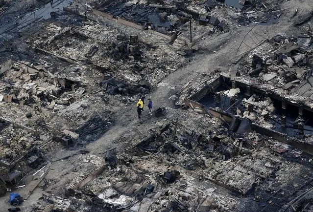 Breezy Point, a tiny beachfront neighborhood told to evacuate before Sandy hit New York, burned down as it was inundated by floodwaters, transforming a quaint corner of the Rockaways into a smoke-filled debris field. (Photo by Mike Groll/Associated Press)
