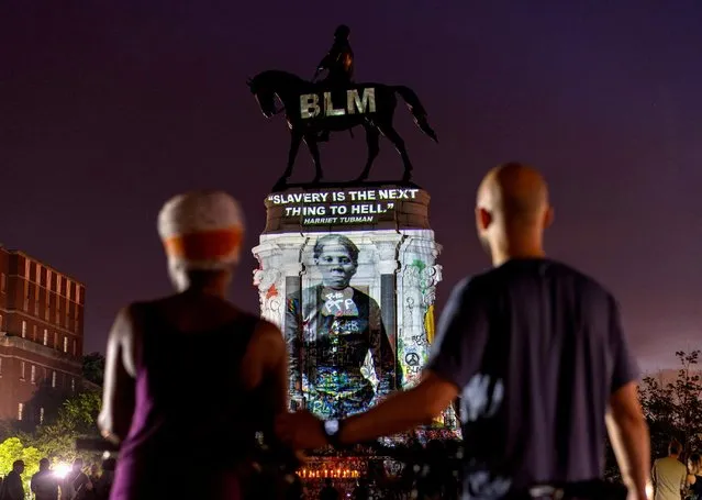 People look on as an image of Harriet Tubman is projected on the statue of Confederate General Robert E. Lee in Richmond, Virginia, U.S. June 20, 2020. (Photo by Jay Paul/Reuters)
