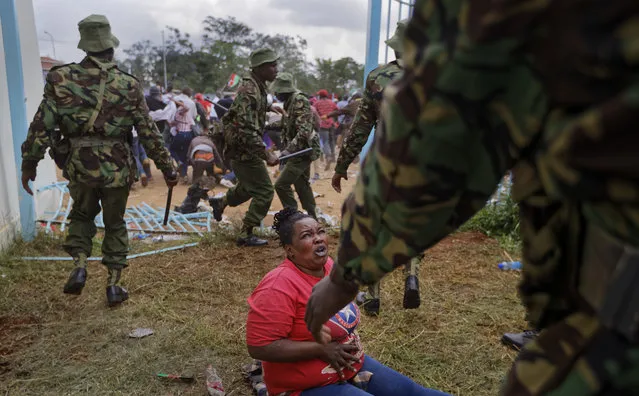 A woman who fell begs for mercy during clashes between rock-throwing supporters of President Uhuru Kenyatta and police at his inauguration ceremony after they tried to storm through gates to get in and were tear-gassed, at Kasarani stadium in Nairobi, Kenya Tuesday, November 28, 2017. (Photo by Ben Curtis/AP Photo)