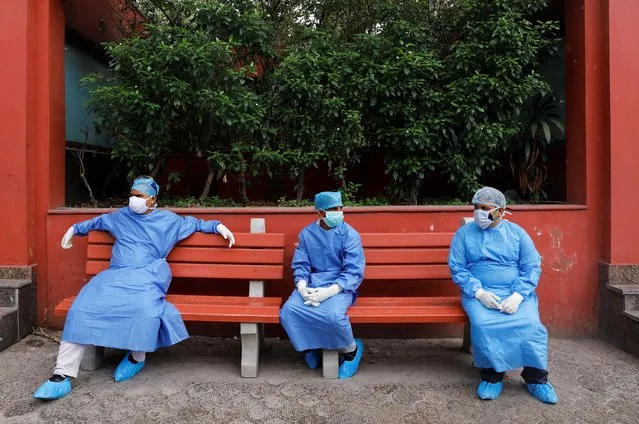 Health workers wearing Personal Protective Equipment (PPE) sit on a bench at a crematorium in New Delhi, India, June 24, 2020. (Photo by Anushree Fadnavis/Reuters)