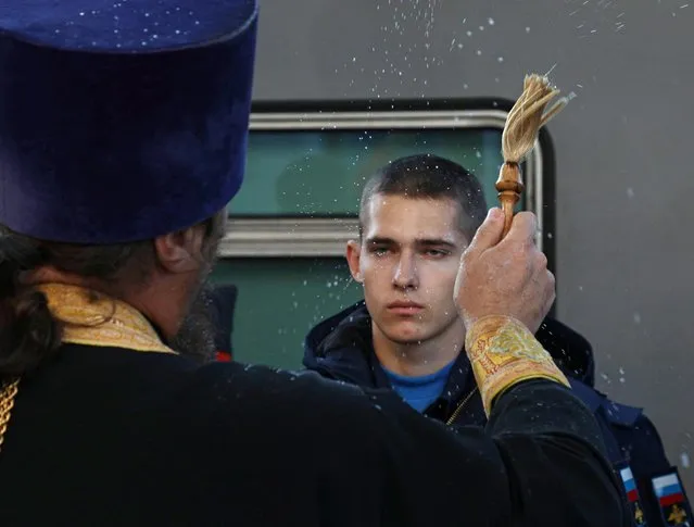An Orthodox priest sprinkles holy water on conscripts at a local railway station during their departure for the garrisons, in Sevastopol, Crimea on November 9, 2022. (Photo by Alexey Pavlishak/Reuters)