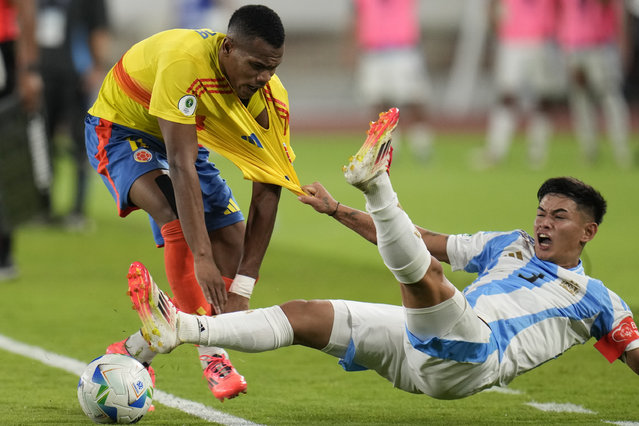 Argentina's Julio Soler, right, grabs onto the jersey of Colombia's Andy Batioja, as he falls on the pitch during a South American U-20 Championship final round soccer match in Caracas, Venezuela, February 10, 2025. (Photo by Matias Delacroix/AP Photo)