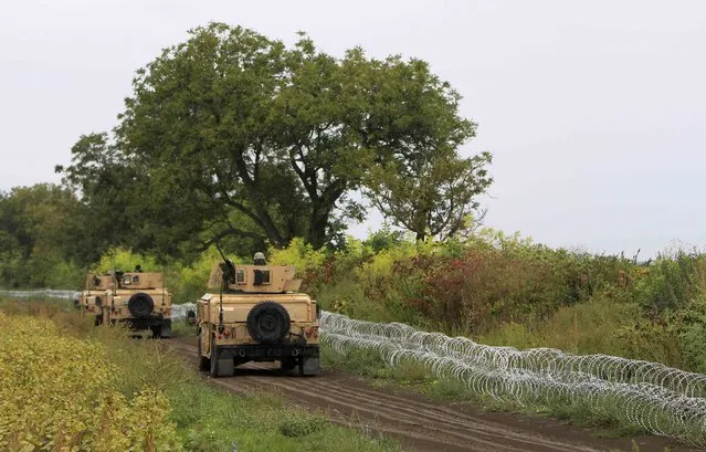 Army vehicles drive along barbed wire at the Hungary-Croatia border near Sarok, Hungary, September 20, 2015. (Photo by Bernadett Szabo/Reuters)