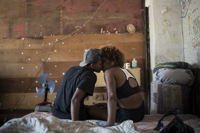 In this September 11, 2017 photo, Jayanne Pessanha, left, and Yara Andrade, kiss in their room in a squatter building that used to house the Brazilian Institute of Geography and Statistics (IBGE) in the Mangueira slum of Rio de Janeiro, Brazil. “Those who are here have faith. They have faith that they will leave this place”, said Pessanha. (Photo by Felipe Dana/AP Photo)