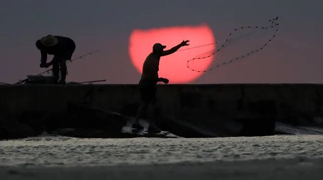 A fisherman casts his net from a jetty in Port Aransas, Texas, at sunrise on September 30, 2017. The costal bend area is still recovering from the effects of Hurricane Harvey. (Photo by Eric Gay/AP Photo)