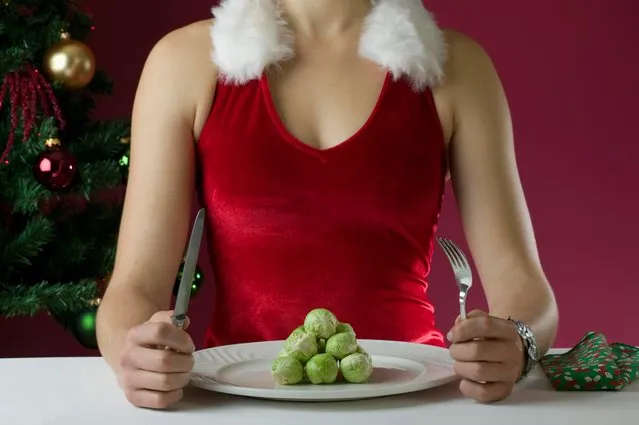 Female in Christmas outfit eating brussels sprouts. (Photo by Tonywestphoto/Getty Images)