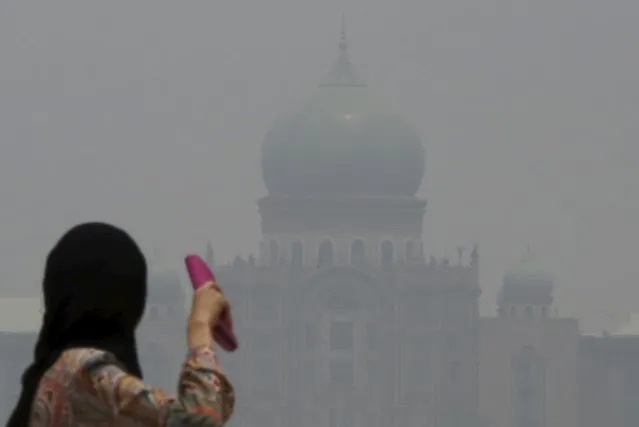 A woman looks towards the Prime Minister's office, which is shrouded in haze, in Putrajaya, Malaysia October 6, 2015. Malaysian Prime Minister Najib Razak has called on Indonesia to take action against people setting fires that have caused choking smoke to drift across the region, with the sky over southern Thailand the latest to be clouded by the pollution. (Photo by Olivia Harris/Reuters)