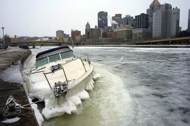 A boat lies partially submerged, surrounded by ice in the Allegheny River in downtown Pittsburgh, Monday, December 26, 2022. (Photo by Gene J. Puskar/AP Photo)