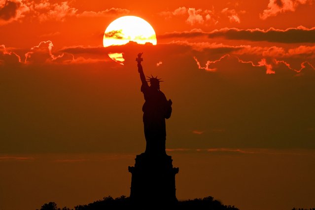 The sun sets behind the Statue of Liberty on July 3, 2025 in New York. (Photo by Angela Weiss/AFP Photo)