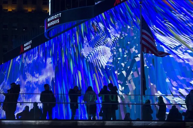 People stand on steps in front of a new digital advertising screen in Times Square, New York, November 18, 2014. (Photo by Carlo Allegri/Reuters)