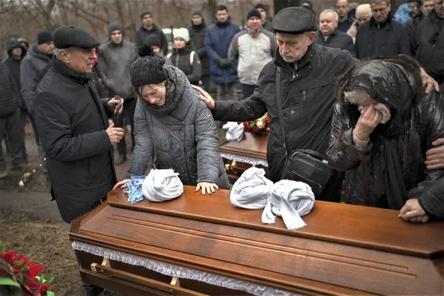 Relatives of Maksym and Nataliia Shvets, a couple who died under the rubble after Russia hit their apartment block with a missile, cry near one of the coffins during a funeral service in Dnipro, Ukraine, Wednesday, January 18, 2023. The death toll from the weekend Russian missile strike on an apartment building, which triggered outrage, has climbed to 45. (Photo by Roman Hrytsyna/AP Photo)