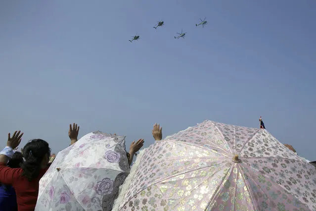North Korean women carrying parasols wave as Hughes MD-500 helicopters fly past during an aerial display on Saturday, September 24, 2016, in Wonsan, North Korea. (Photo by Wong Maye-E/AP Photo)