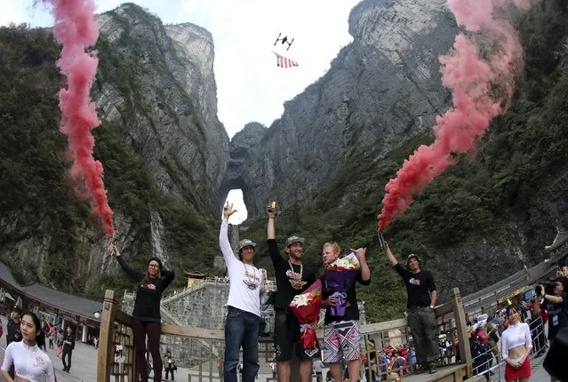 Winner Noah Bahnson of the U.S. (C), second-placed Julian Boulle of South Africa (L) and third placed Nathan Jones of Australia pose for photographs at the podium after the fourth World Wingsuit Flying Tournamentat at the Tianmen Mountain National Park in Zhangjiajie, Hunan province, China, October 18, 2015. (Photo by Reuters/China Daily)