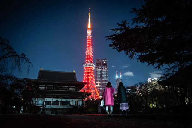 People visit Zojoji temple as Tokyo Tower is lit in red to celebrate the Chinese Lunar New Year in Tokyo on January 21, 2023. (Photo by Yuichi Yamazaki/AFP Photo)