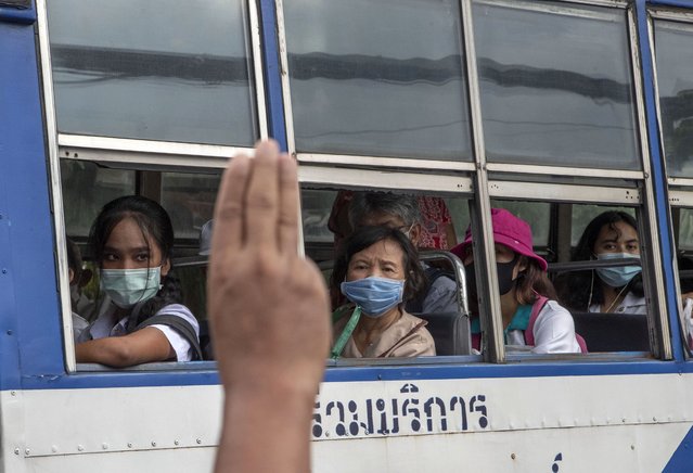 A pro-democracy protester flashes a three-fingered salute, the movement's symbol of resistance, as bus passengers watch during a protest outside the Parliament in Bangkok, Thailand, Thursday, September 24, 2020. Lawmakers in Thailand are expected to vote Thursday on six proposed amendments to the constitution, as protesters supporting pro-democratic charter reforms gathered outside the parliament building. (Photo by Gemunu Amarasinghe/AP Photo)