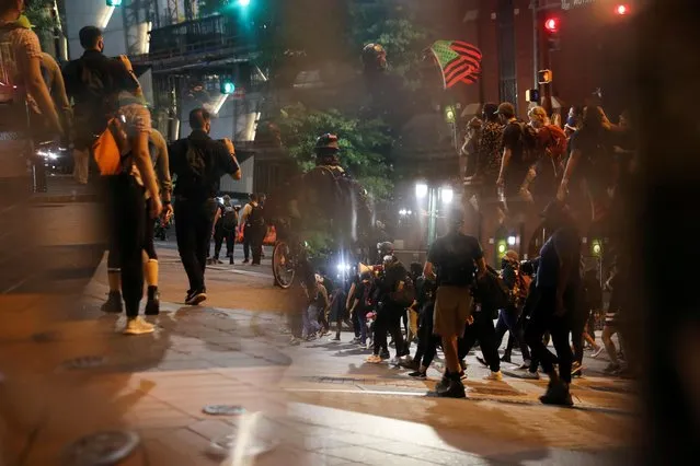 Demonstrators are seen reflected in the mirrors of the Charlotte's Firebird Statue as they take part in a protest in downtown Charlotte, North Carolina, U.S., August 22, 2020. (Photo by Leah Millis/Reuters)