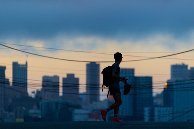 A person cross an empty street during sunset in San Francisco, California, U.S., July 29, 2025. (Photo by Carlos Barria/Reuters)