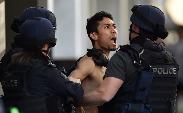 An unidentified man (C) reacts as he is detained by special police officers outside a restaurant in central Melbourne, Australia, 27 October 2015. Police were called to the restaurant at the corner of Latrobe and Queen Street at 1pm local time on 27 October after a man barricaded himself inside. Police arrested the man after he exited the building just after 3pm local time, holding his hands above his head, media reported. (Photo by Julian Smith/EPA)