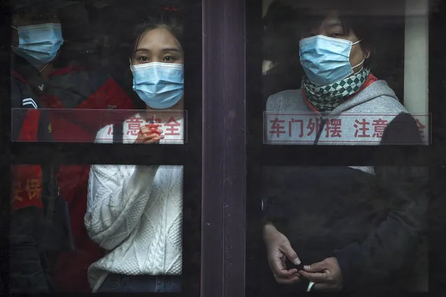 Commuters wearing face masks to help curb the spread of the coronavirus look out from a traveling bus during the morning rush hour in Beijing, Monday, October 26, 2020. Schools and kindergartens have been suspended and communities are on lockdown in Kashgar, a city in China's northwest Xinjiang region, after more than 130 asymptomatic cases of the coronavirus were discovered. (Photo by Andy Wong/AP Photo)