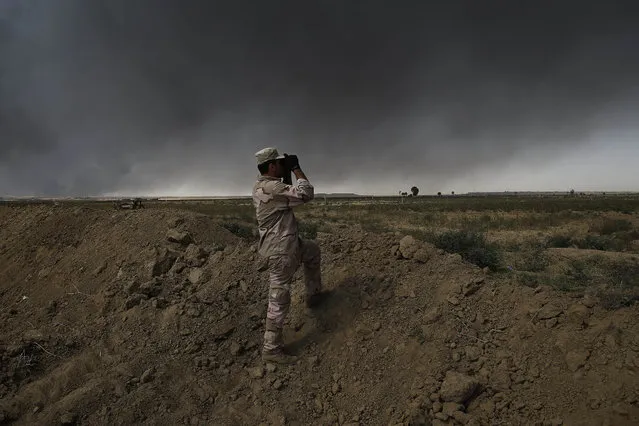 An Iraqi army member looks toward Islamic State group territory outside Qayyarah on Tuesday October 4, 2016.  Qayyarah has become an important staging ground for military and humanitarian efforts ahead of the Mosul operation. (Photo by Bram Janssen/AP Photo)