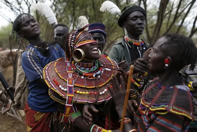 Pokot men and women hold a girl before she is taken away by a group of men to be married to a member of their community after the group came to take her from her family home, about 80 km (50 miles) from the town of Marigat in Baringo County December 7, 2014. (Photo by Siegfried Modola/Reuters)