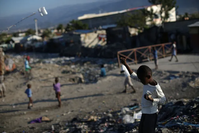A boy plays with a piece of styrofoam as a kite in Port-au-Prince, March 3, 2018. (Photo by Andres Martinez Casares/Reuters)