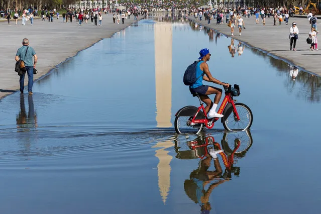 A visitor rides a bicycle through a partially-drained reflecting pool during the annual Cherry Blossoms Kite Fest on the National Mall, in Washington, U.S., March 26, 2023. (Photo by Tom Brenner/Reuters)