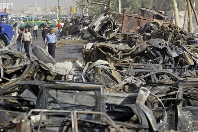 This August 29, 2009 file photo shows Iraqis walking past destroyed cars after a massive bomb attack in front of the Foreign Ministry in Baghdad, Iraq. The country is moving toward some level of stability. But it came only after years that pushed Iraq perilously close to civil war between the Sunnis who lost power after Saddam's fall and the majority Shiites who took control of the aftermath. (Photo by Khalid Mohammed/AP Photo)