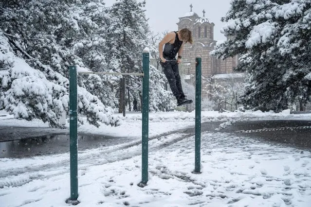 A man exercises on an outdoor gym equipment at Tasmajdan Park during rare spring snowfall, in central Belgrade, Serbia on April 4, 2023. (Photo by Marko Djurica/Reuters)