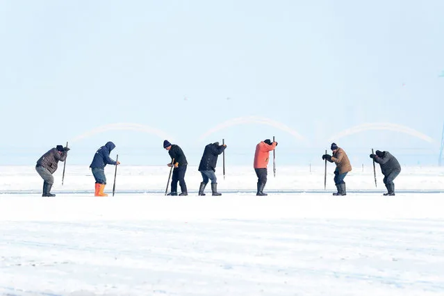 Workers uses picks to cut ice blocks from the frozen Songhua river in Harbin in China's northeastern Heilongjiang province on December 9, 2020, as ice is collected for the Second Harbin Ice Harvest Festival. (Photo by AFP Photo/China Stringer Network)
