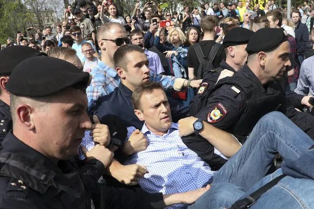 Russian police carrying struggling opposition leader Alexei Navalny, center, at a demonstration against President Vladimir Putin in Pushkin Square in Moscow, Russia, Saturday, May 5, 2018. Thousands of demonstrators denouncing Putin's upcoming inauguration into a fourth term gathered Saturday in the capital's Pushkin Square. (Photo by AP Photo/Stringer)