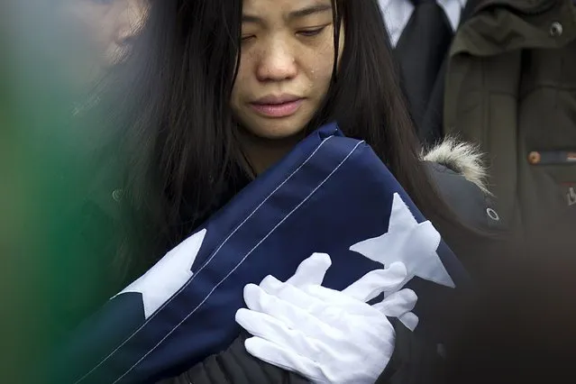 Widow Pei Xia Chen clutches the folded flag of slain New York Police Department officer Wenjian Liu as his casket departs his funeral in the Brooklyn borough of New York January 4, 2015. (Photo by Carlo Allegri/Reuters)