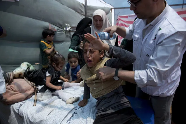 Medics treat Palestinian children suffering from teargas inhalation during a protest near Beit Lahiya, Gaza Strip, Monday, May 14, 2018. Israeli soldiers shot and killed dozens of Palestinians during mass protests along the Gaza border on Monday. It was the deadliest day there since a devastating 2014 cross-border war and cast a pall over Israel's festive inauguration of the new U.S. Embassy in contested Jerusalem. (Photo by Dusan Vranic/AP Photo)