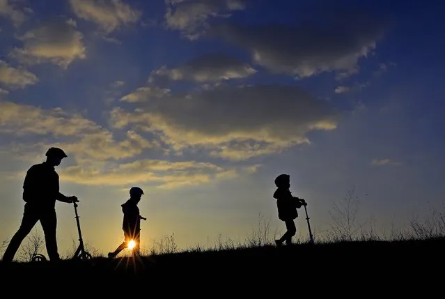 A father and his sons, as seen against the sun, walk at sunset on the side dam of Vacaresti wild park, in Bucharest, Romania, 15 November 2020. (Photo by Robert Ghement/EPA/EFE)