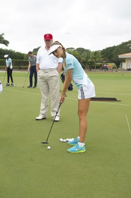 Donald Trump gives some putting tips to Diana Harkusha, Miss Ukraine 2014 at the 63rd annual Miss Universe Pageant in Miami, Florida in this January 12, 2015 handout photo provided by Miss Universe Organization. (Photo by Reuters/Miss Universe Organization)