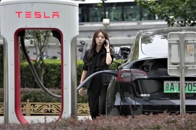 A worker stands next to a Tesla being charged in Beijing, Tuesday, May 30, 2023. China’s foreign minister met Tesla Ltd. CEO Elon Musk on Tuesday and said strained U.S.-Chinese relations require “mutual respect”, while delivering a message of reassurance that foreign companies are welcome. (Photo by Ng Han Guan/AP Photo)