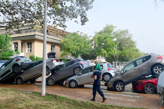 Residents walk near piled up cars following flood in Picanya, near Valencia, eastern Spain, on October 30, 2024. Floods triggered by torrential rains in Spain's eastern Valencia region has left 51 people dead, rescue services said on October 30. (Photo by Jose Jordan/AFP Photo)
