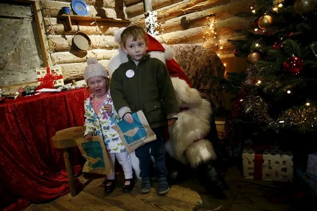 Two-year-old Eliza and her four-year-old brother James pose for a picture with actor John Field, dressed as Santa Claus, at a Christmas grotto at the Wetland Centre in London, Britain, December 5, 2015. (Photo by Stefan Wermuth/Reuters)