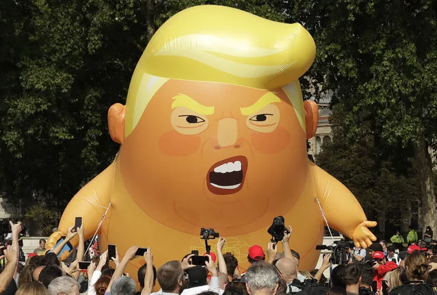 A six-meter high cartoon baby blimp of U.S. President Donald Trump is flown as a protest against his visit, in Parliament Square in London, England, Friday, July 13, 2018. Trump is making his first trip to Britain as president after a tense summit with NATO leaders in Brussels and on the heels of ruptures in British Prime Minister Theresa May's government because of the crisis over Britain's exit from the European Union. (Photo by Matt Dunham/AP Photo)