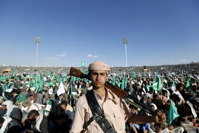 Houthi militant stands guard as supporters of the Houthi movement sit during a rally marking the birth anniversary of the Prophet Mohammed in Yemen's capital Sanaa, December 23, 2015. (Photo by Khaled Abdullah/Reuters)