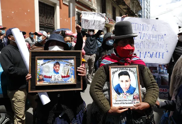 Women hold photos of victims killed during clashes that happened between security forces and supporters of former President Evo Morales when Bolivia's former Interim President Jeanine Anez was in power, outside the police station where she is being held in La Paz, Bolivia, Sunday, March 14, 2021. Anez, who led Bolivia for a year, was arrested Saturday as officials of the restored leftist government pursue those involved in the 2019 ouster of socialist leader Evo Morales, which they regard as a coup, and the administration that followed. (Photo by Juan Karita/AP Photo)