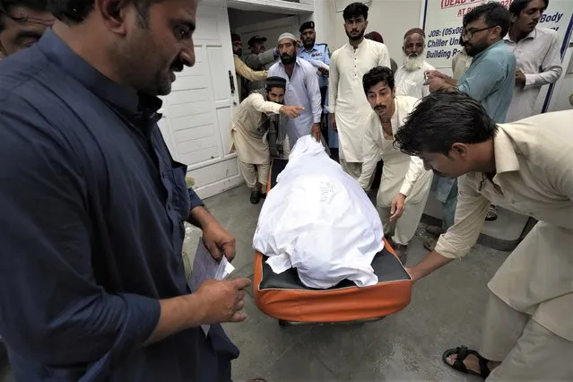 Relatives carry the body of a man killed after a wall collapse due to monsoon rains into an ambulance at PIMS hospital in Islamabad, Pakistan, Wednesday, July 19, 2023. Multiple workers were killed early Wednesday after a portion of the outer wall of a sprawling compound collapsed after being weakened by rains near an under-construction bridge on the outskirts of Pakistan's capital, Islamabad, police and rescue officials said. (Photo by Rahmat Gul)/AP Photo